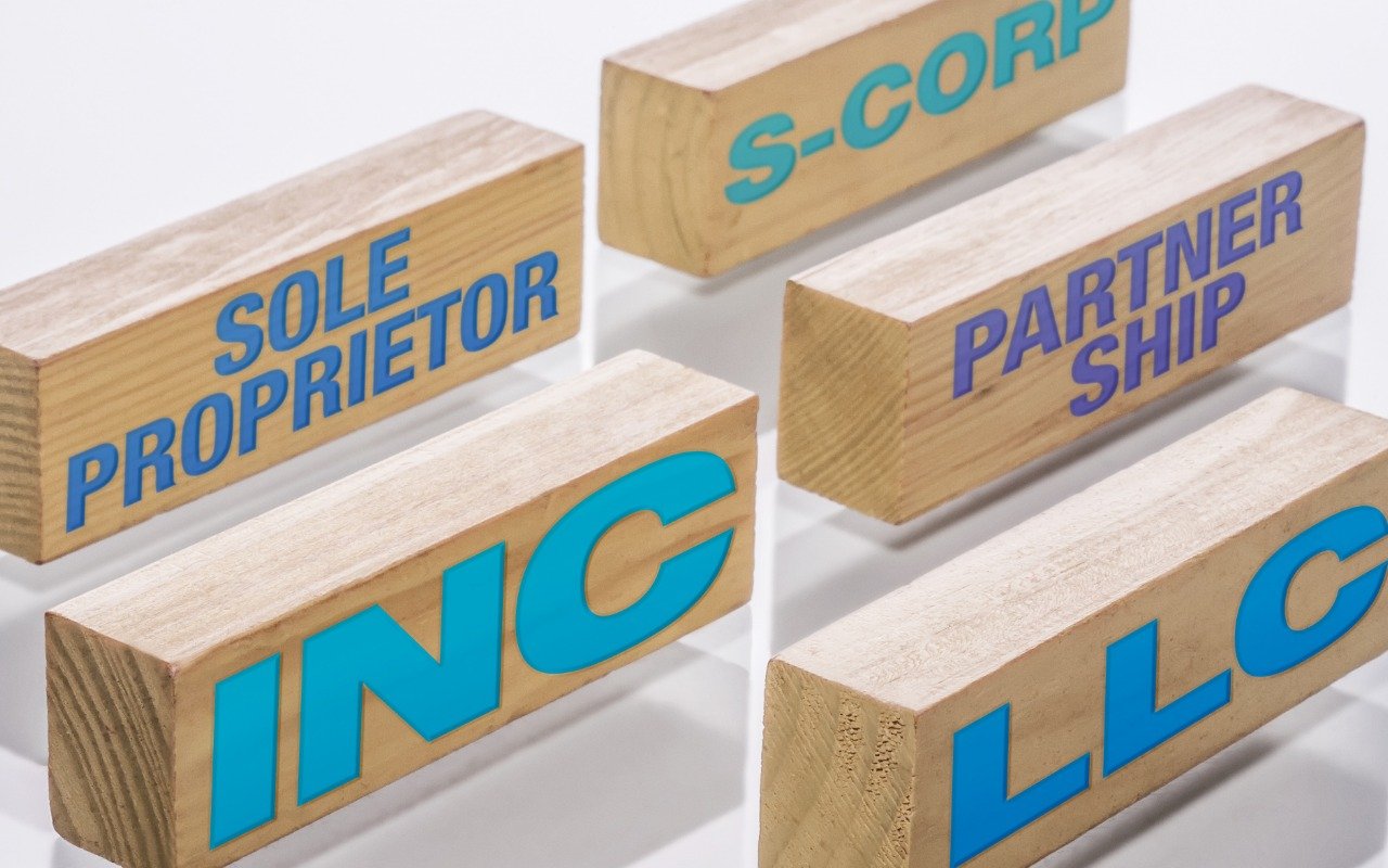 Wooden blocks labeled LLC, INC, S-Corp, Sole Proprietor, and Partnership