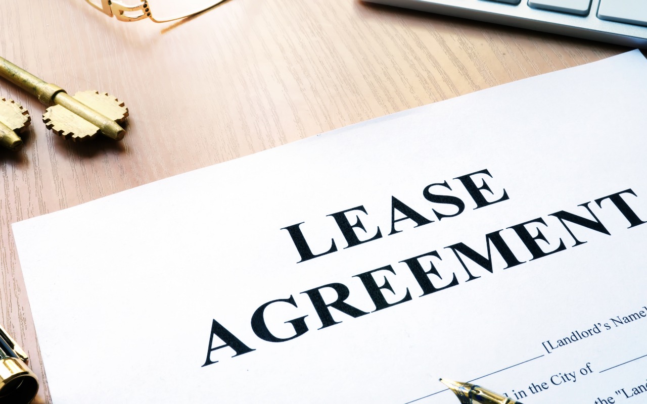 Close-up of a lease agreement document on a wooden desk with pen and keys